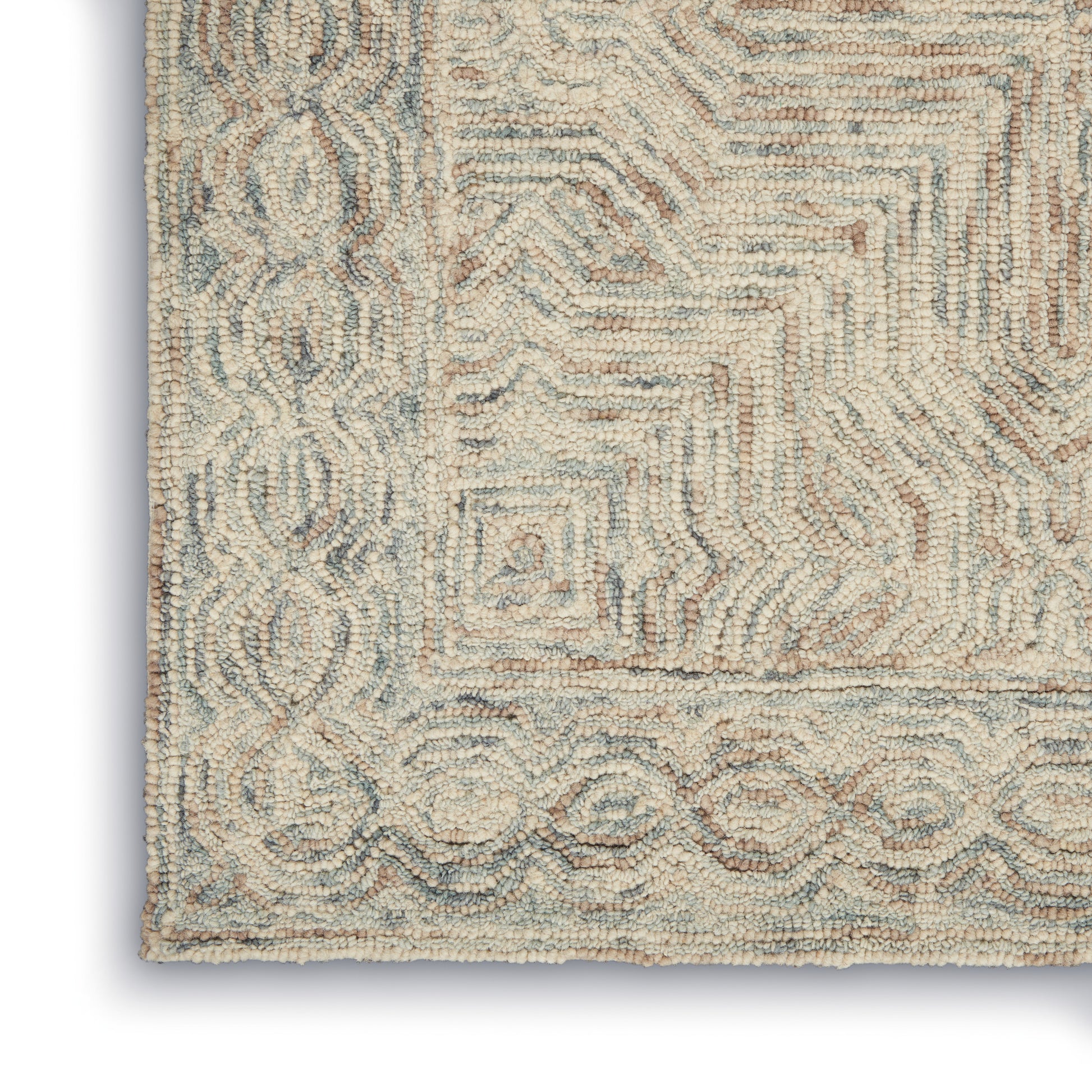 Corner of a cream shag rug with pale blue accents, featuring a geometric border of circles and subtle concentric squares.