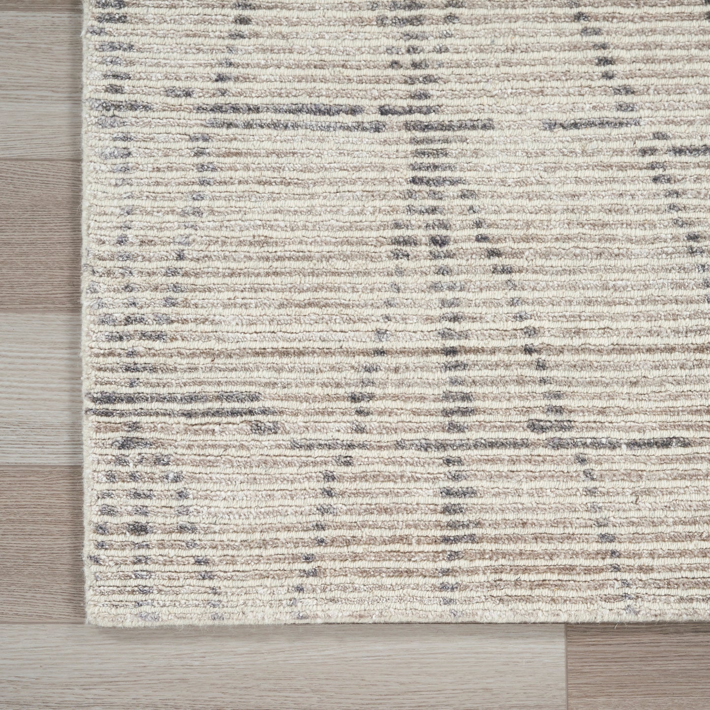 Cream beige low-pile area rug with subtle gray linear stripes on light wood floor.