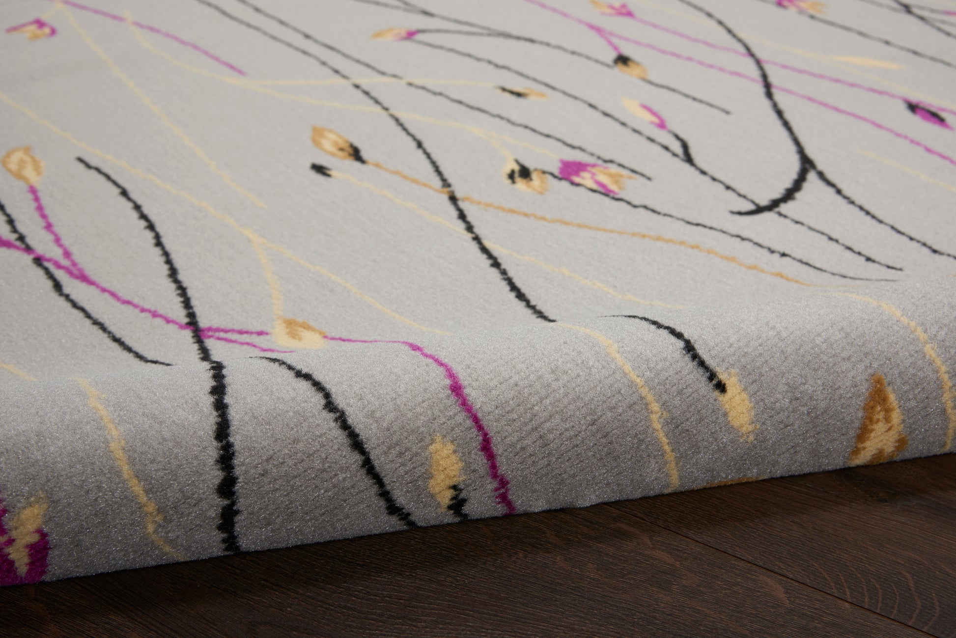 Gray modern 8' round rug with abstract black, purple, and yellow curves; plush pile and edge resting on a dark wood floor.