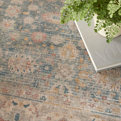 Distressed blue and beige Persian-style rug with pink and yellow motifs.