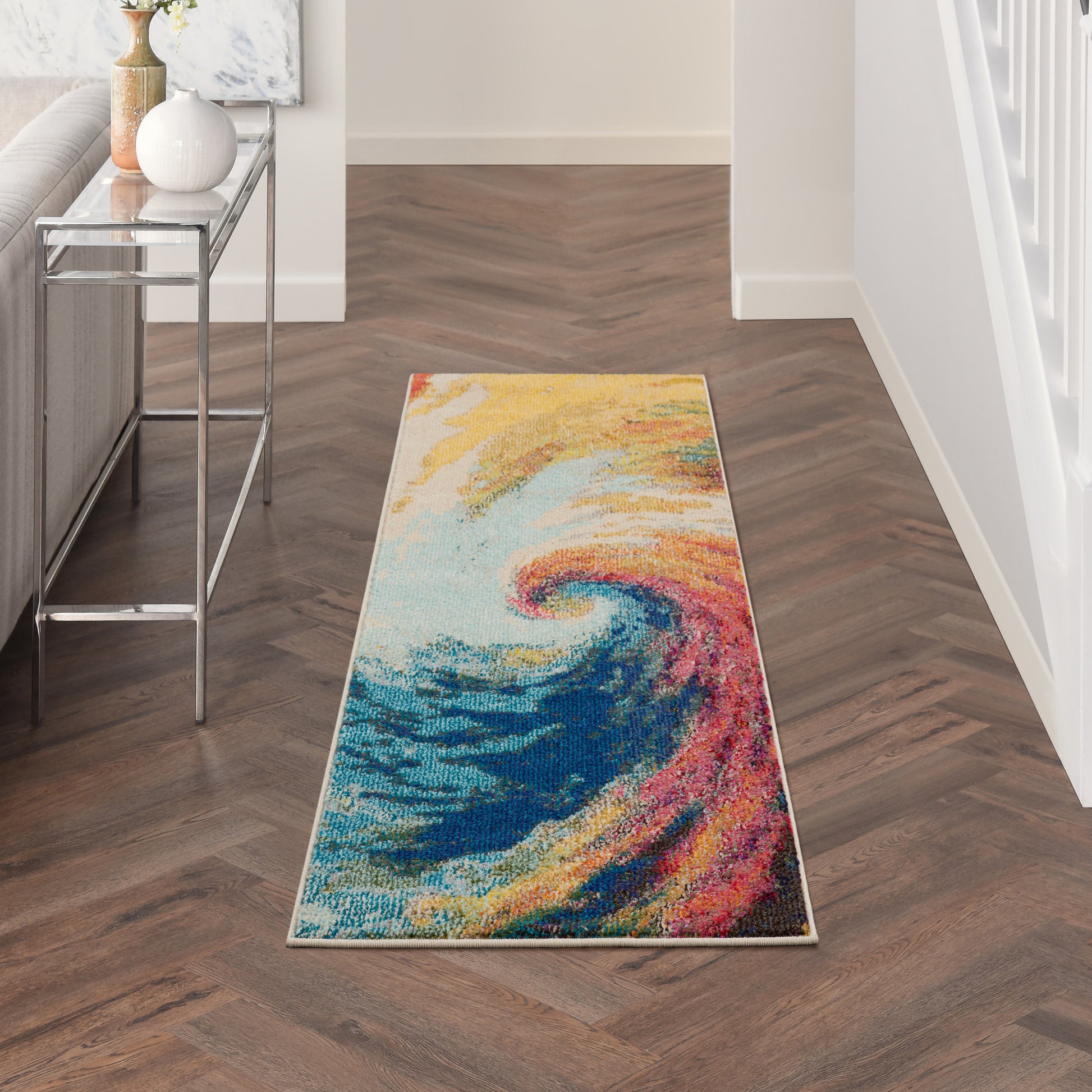 Long hallway runner rug with a vivid abstract rainbow swirl in blues, yellows, and oranges.
