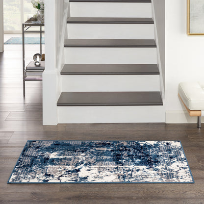 Abstract blue and white area rug on dark wood floor in front of a white staircase, modern living area.
