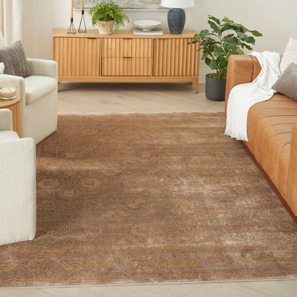 Living room with a brown ornate rug, light wood sideboard, cream chairs and a tan sofa, plus green potted plants.