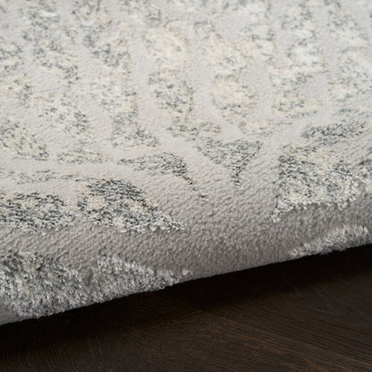 Soft gray and ivory patterned shag rug with thick plush pile on dark wooden floor.