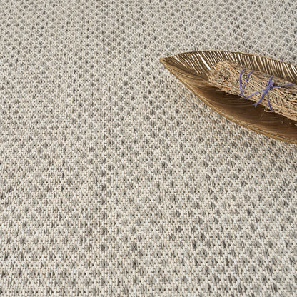 Beige-gray woven textile with small repeating pattern; wooden leaf tray holding a dried grass bundle bound with purple string.