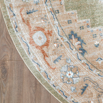 Partially visible round oriental rug with beige-orange field, blue floral motifs & green border on hardwood floor.