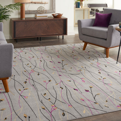 Light-gray rectangular area rug with black, pink and gold vine patterns in a modern living room with gray chairs.