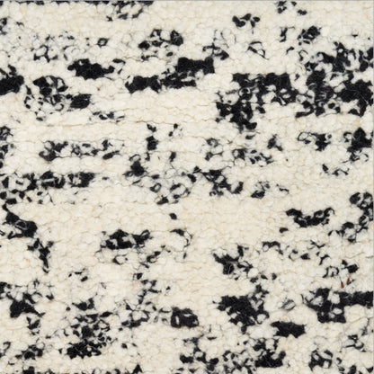 Cream boucle fabric with black irregular speckles; soft, textured textile for upholstery or garments.