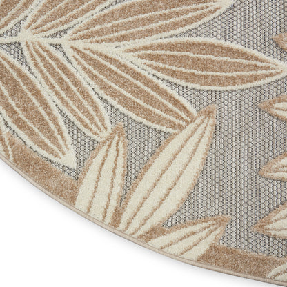 Round rug with tan leaf motifs on gray geometric backdrop; plush, textured pile.