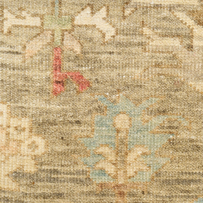Close-up of a beige oriental rug with muted floral motifs in blue-green and red accents, woven pile texture.