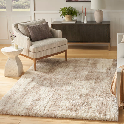 Cream shag area rug on light wood floor with beige striped armchair and dark wood console.