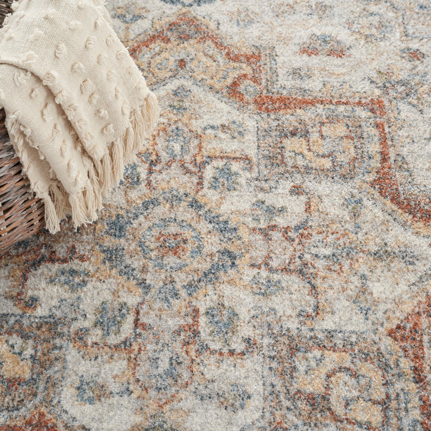 Muted oriental rug in cream, blue and rust with motifs.