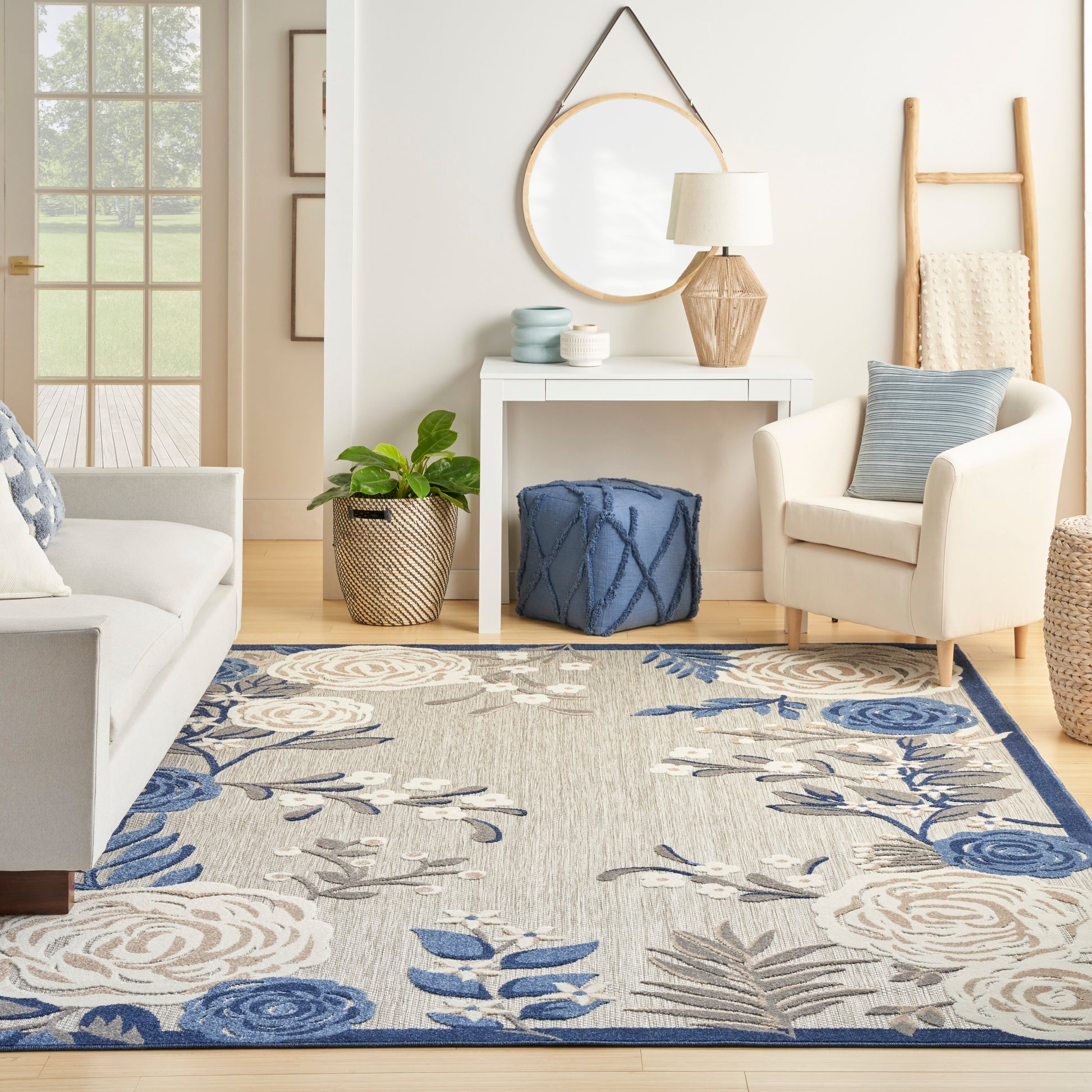 Cozy living room with cream seating, blue cushions, floral blue-beige rug, white console, round mirror, wooden accents.