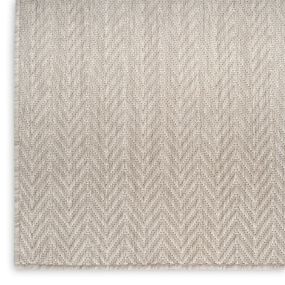 Beige chevron-patterned woven rug with a textured surface, neutral cream tones.