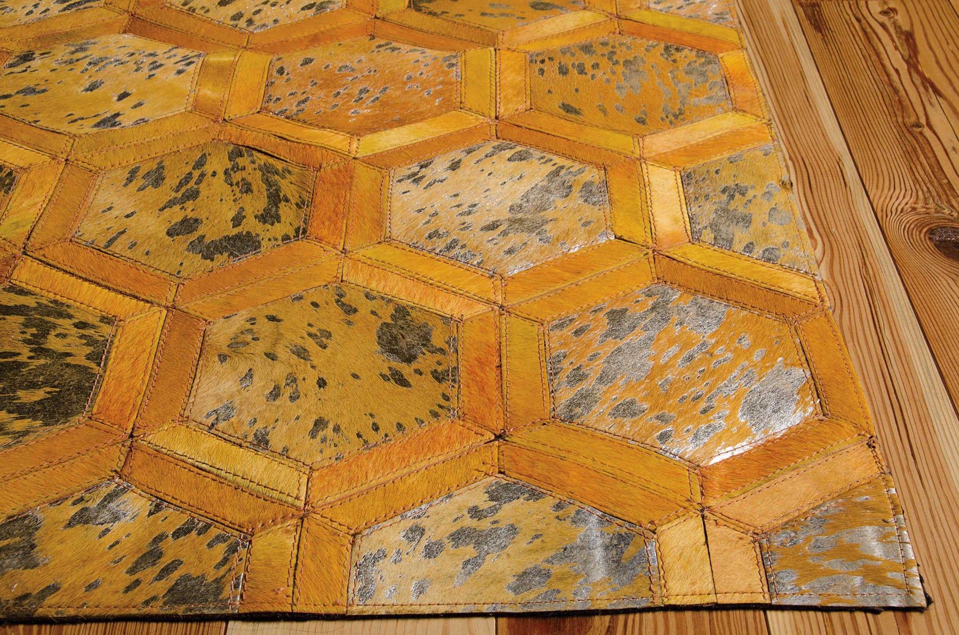 Golden honeycomb patchwork rug with yellow leather strips and metallic cowhide panels.