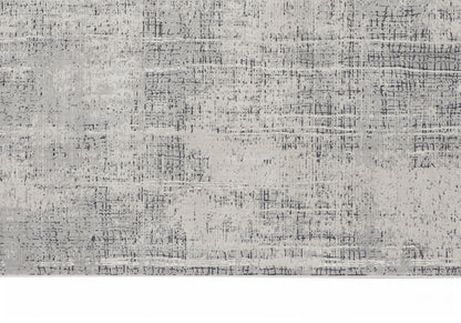 Rectangular area rug in muted gray tones with an abstract distressed pattern and subtle speckling.