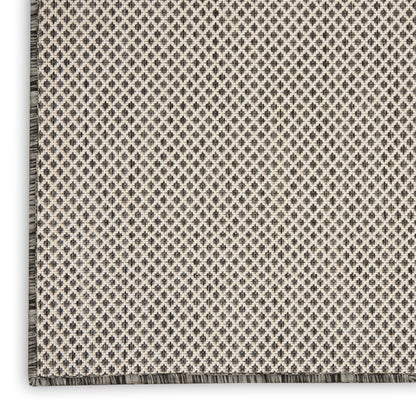 Beige and gray woven rug with tiny diamond lattice pattern and fringe along edge.
