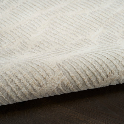 Cream textured area rug with raised linear rib pattern, soft pile on dark wood floor.