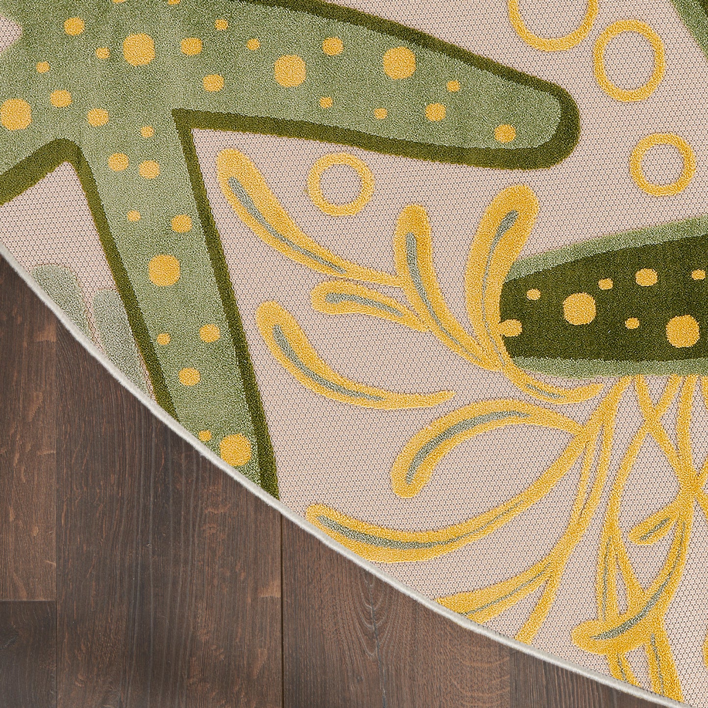 Decorative area rug with olive-green and yellow floral motif on beige background; curved edge reveals wood floor.