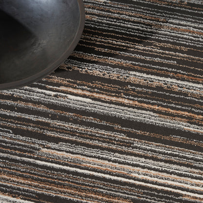 Dark round metal pan resting on a striped black, white & tan area rug; modern industrial decor