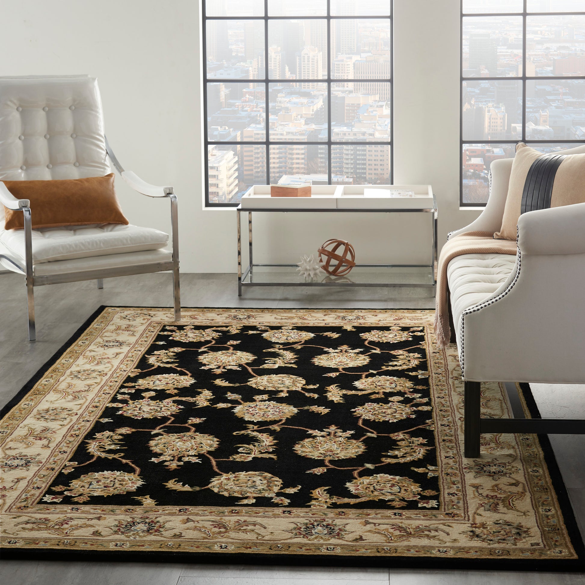 Living room with black and gold floral rug, beige border, white tufted chairs, brown pillow, white metal-frame table, skyline