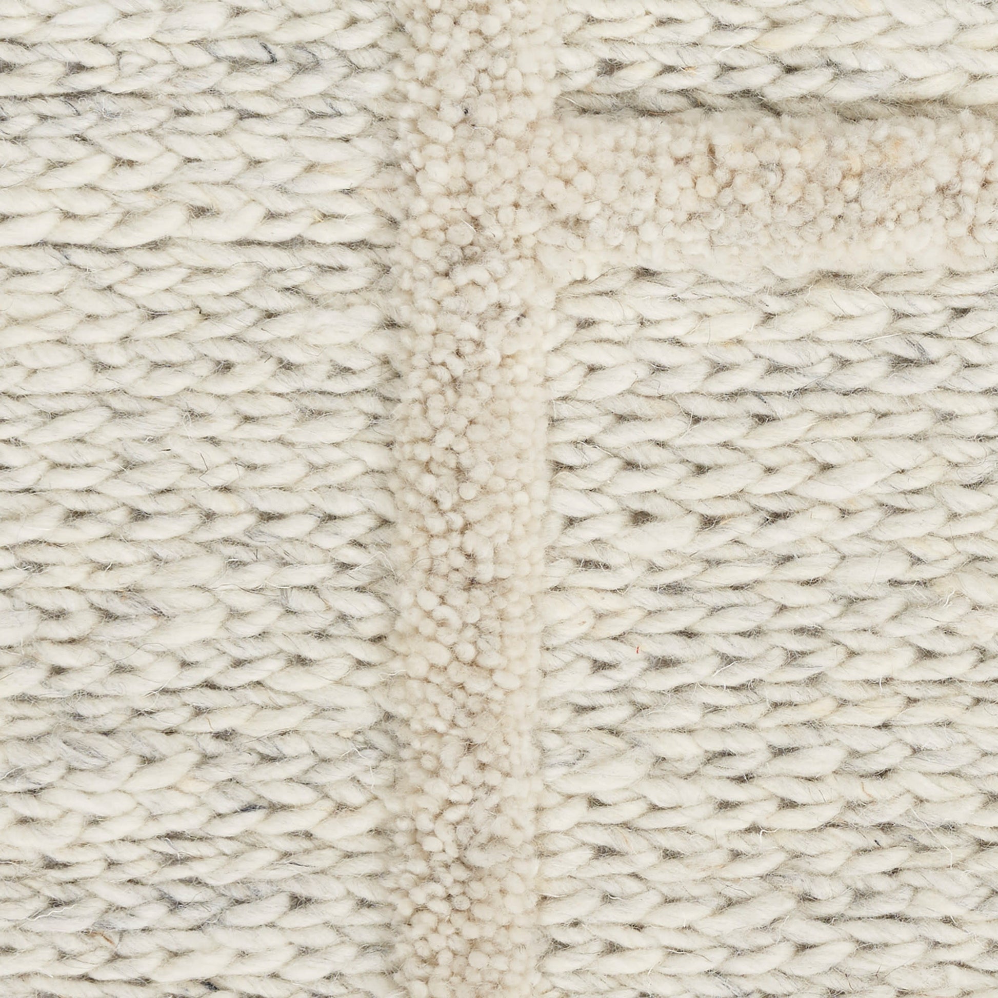 Cream rug close-up with cable-like texture and raised seam, cozy and soft.