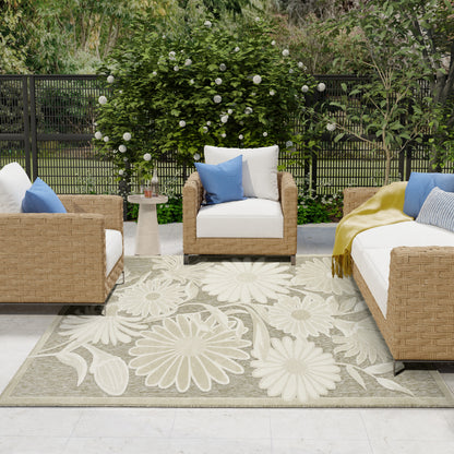 Outdoor beige floral rug on a patio with wicker seating, white cushions and blue pillows, and a round side table.