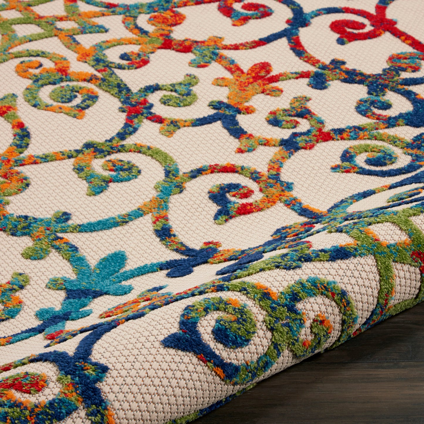 Vibrant ornate scrollwork rug on beige background; woven tapestry texture in blues, greens, oranges and reds.
