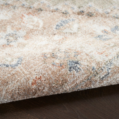 Beige patterned round area rug (5' diameter) with soft pile and blue, orange, gray floral motifs on dark wood floor.