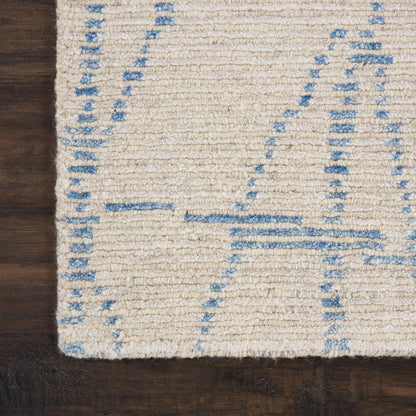 Cream textured rug with pale blue geometric lines on dark wood floor.