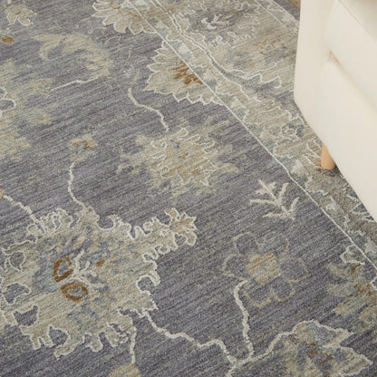 Blue-gray area rug with beige floral medallion pattern; traditional damask style near a white sofa.