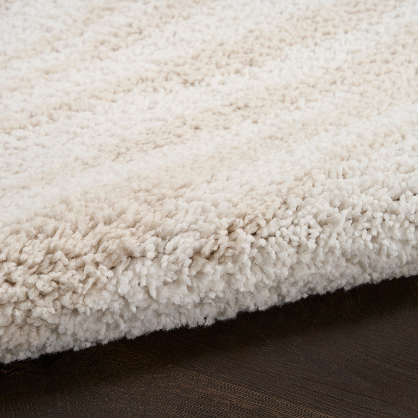 Cream shag rug with thick plush pile on dark wood floor.