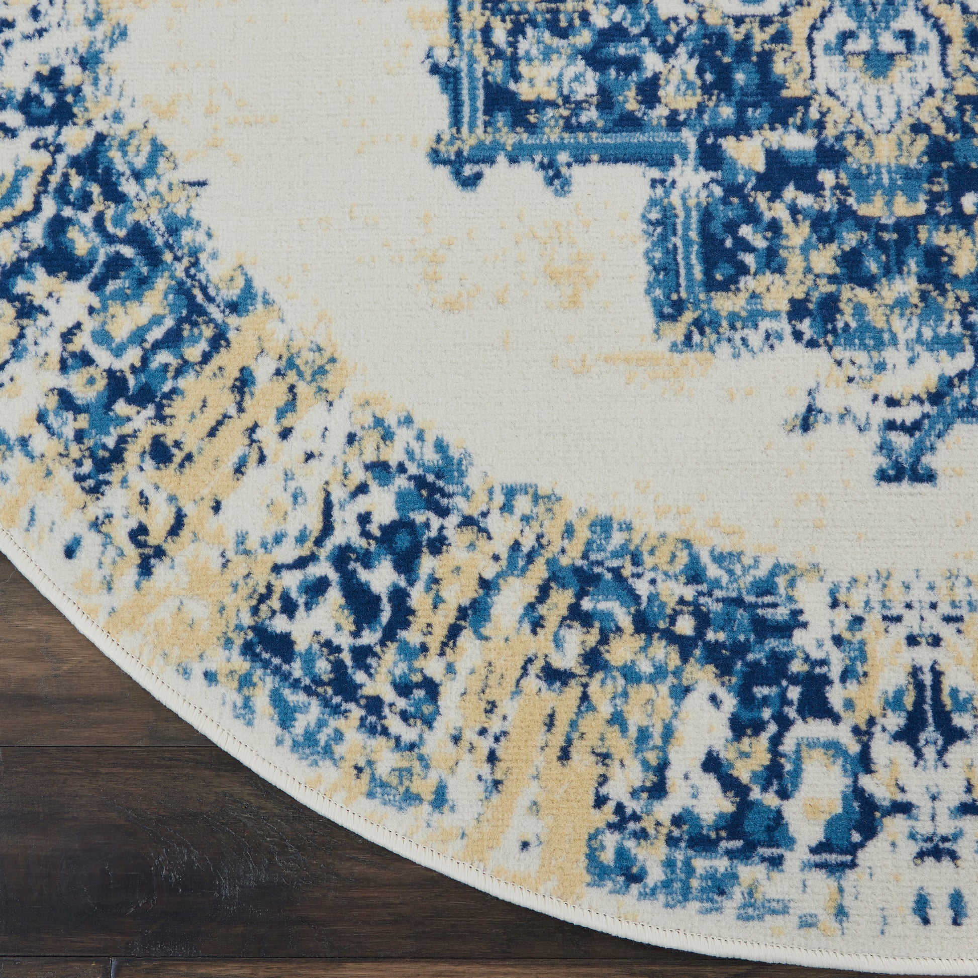 Round area rug with blue, ivory and tan abstract pattern on wood floor
