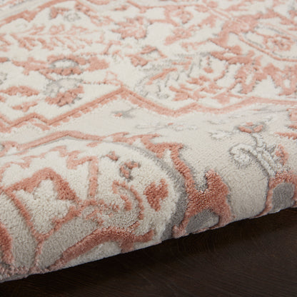 Close-up of a plush tufted rug with peach-pink floral motif on light gray background; soft, modern-traditional style.