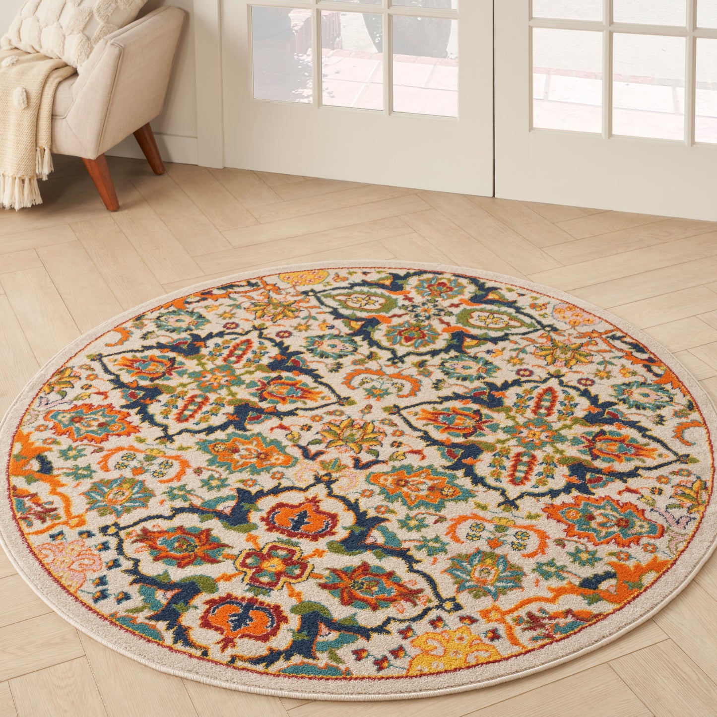 Round oriental-style rug with cream base and vibrant orange, teal, navy, and gold florals; cozy living room decor.
