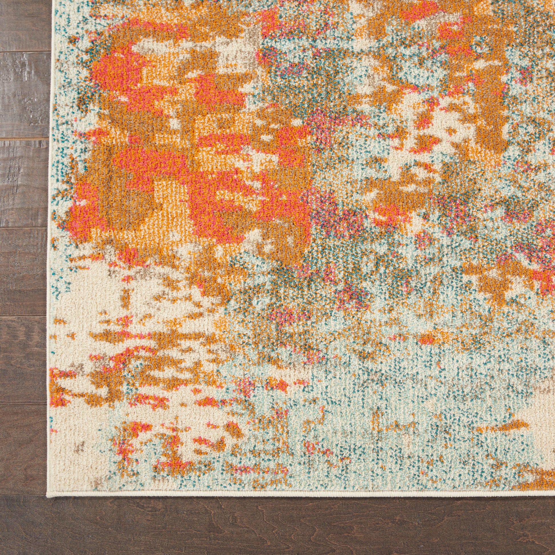 Abstract multicolor area rug with orange, teal, pink and cream blotches on a beige background, laid on dark wood floor.
