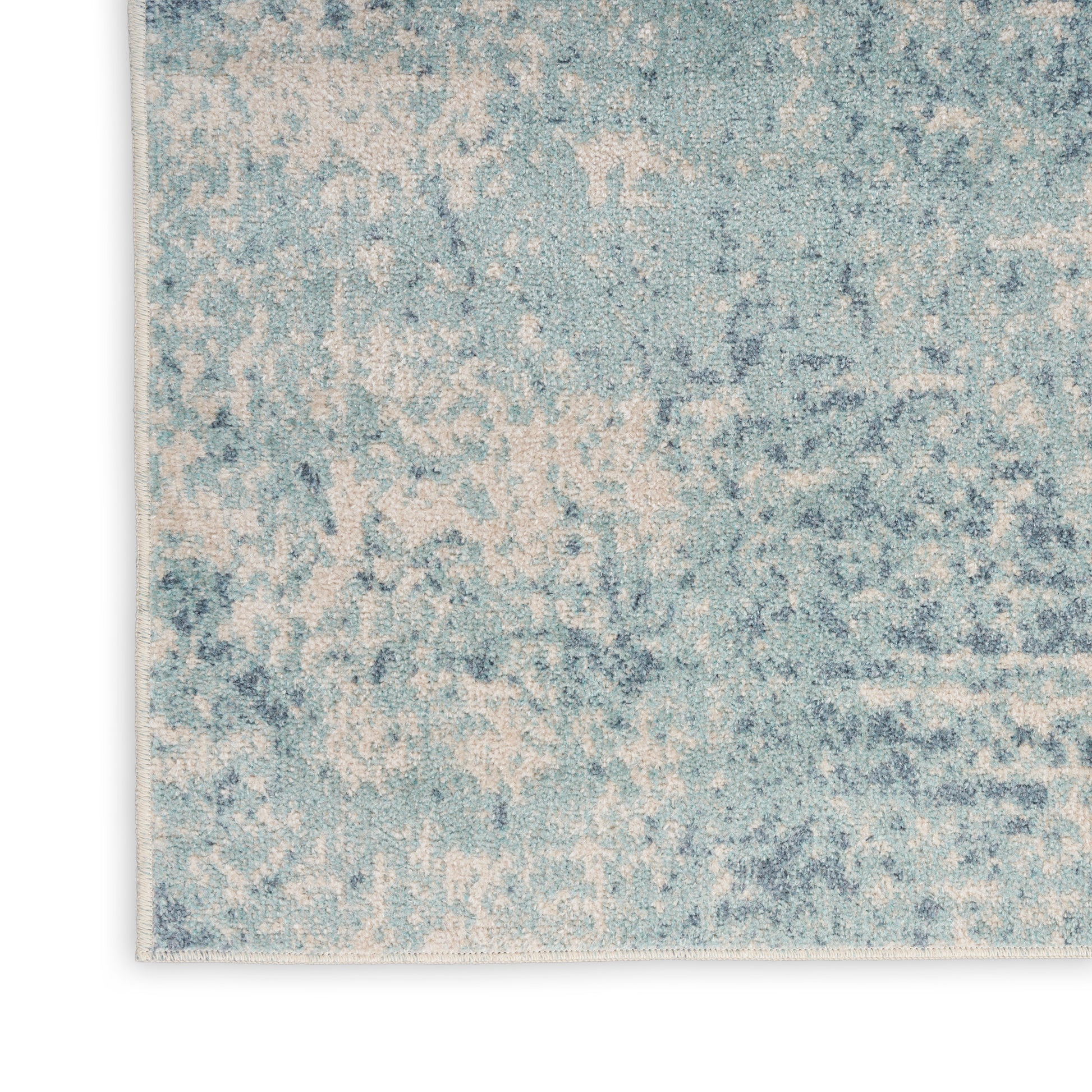 Blue and cream distressed rug corner with a mottled abstract pattern and soft textured pile.
