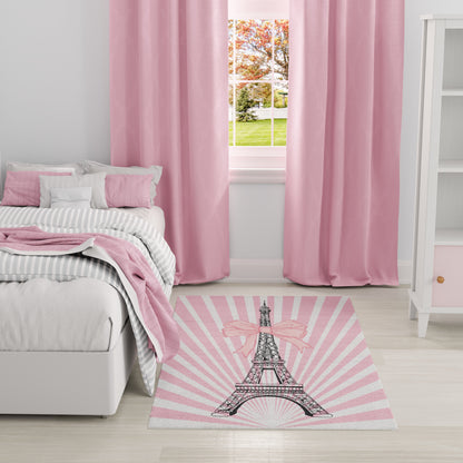 Pastel pink bedroom with pink curtains, striped gray bedding, and a pink rug featuring the Eiffel Tower.