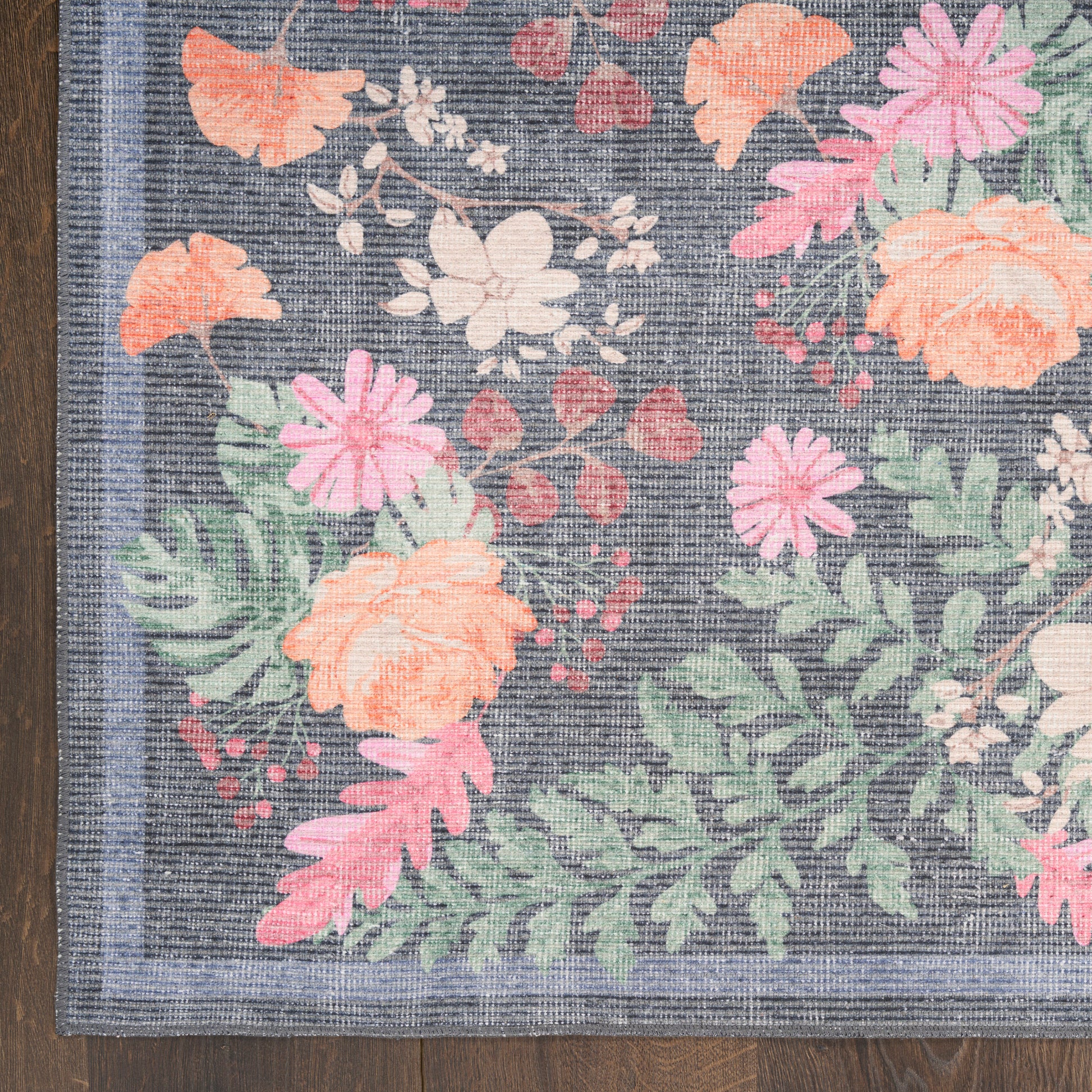 Dark navy woven floral rug with orange, pink, and peach flowers and green leaves, light blue border.