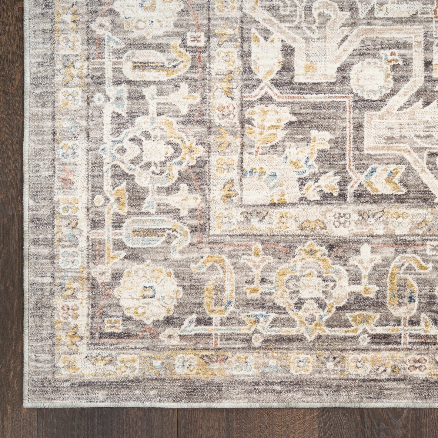 Rectangular gray oriental-style area rug with ivory and pale yellow floral motifs on dark wood floor.