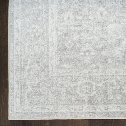 Light gray distressed area rug with subtle oriental pattern on dark wood floor; pale border visible.