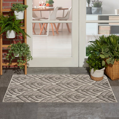 Gray leaf rug on dark tile, plants in baskets beside glass doors opening to a bright dining room.