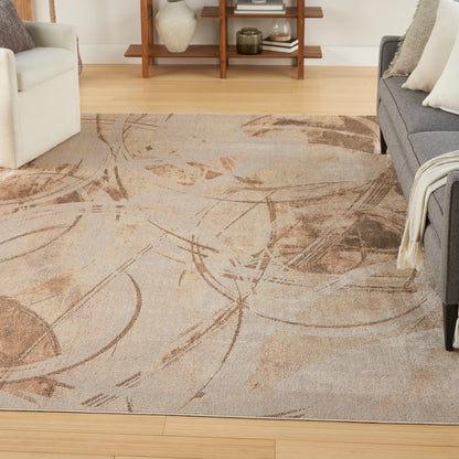 Abstract beige and brown patterned area rug in a living room with cream and gray sofas.