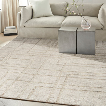 Beige geometric-pattern area rug in a modern living room with a light sofa and concrete-gray cube side tables.
