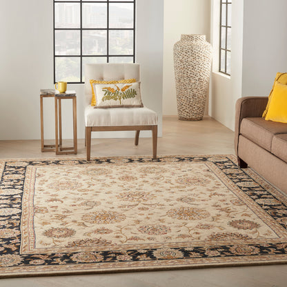 Beige oriental woven rug with floral motifs and dark border in a sunlit living room with cream chair and yellow accents.