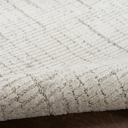 Cream textured rug with a subtle diamond lattice pattern; low-pile cut-loop rug on dark wood floor.