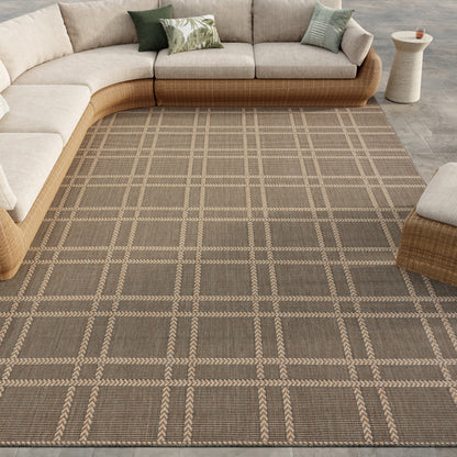 Curved tan wicker sectional with beige cushions on a brown plaid woven rug; coastal neutral living room.