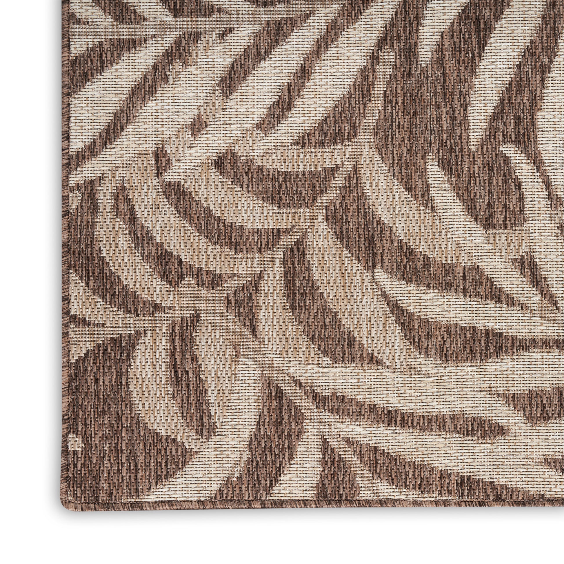 Close-up of brown and beige woven rug with a leafy botanical pattern and textured weave.