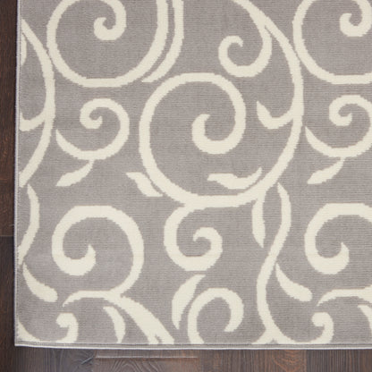 Gray rug with white swirling scroll pattern and thin border on dark wood floor.