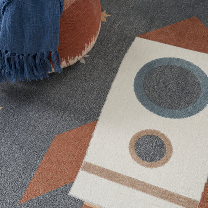 Blue fringed throw draped over a mid-century rug with beige, brown and blue geometric shapes and circular motifs.